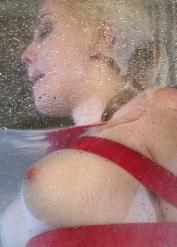 Blonde girl Annette Schwarz is suspended in a glass box while being doused with