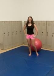 Czech brunette Sandy Ambrosia sits on an exercise ball in the locker room