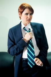 Short-haired red head Lily Cade removes a suit and tie to pose nude in boots